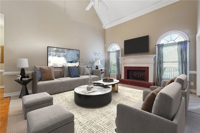 living room with ceiling fan, ornamental molding, a fireplace, and high vaulted ceiling