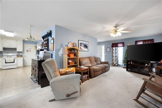 living room featuring ceiling fan with notable chandelier, light colored carpet, and a textured ceiling