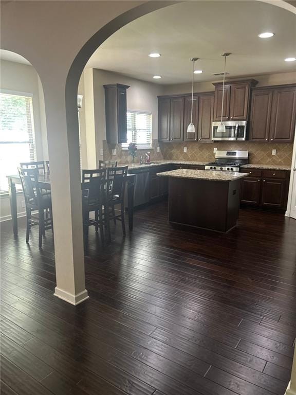 1749 Misselthrush Ln, Mcdonough, GA 30253 - kitchen with stainless steel appliances, a kitchen island, tasteful backsplash, arched walkways, and dark wood finished floors