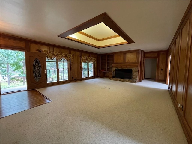 unfurnished living room with a stone fireplace and a tray ceiling