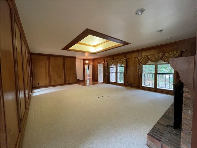 unfurnished living room with a raised ceiling, light colored carpet, and a fireplace