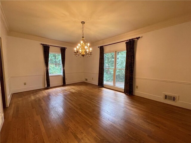 unfurnished room with an inviting chandelier, plenty of natural light, and dark hardwood / wood-style flooring