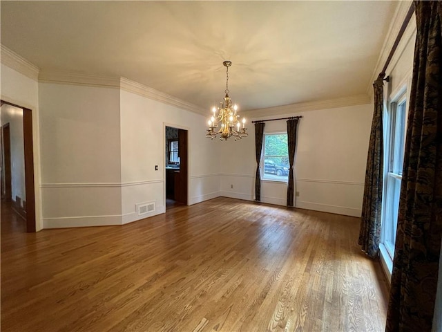 unfurnished room with crown molding, a chandelier, and hardwood / wood-style flooring