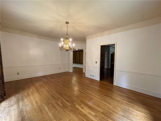 unfurnished room featuring ornamental molding, a notable chandelier, and dark wood-type flooring