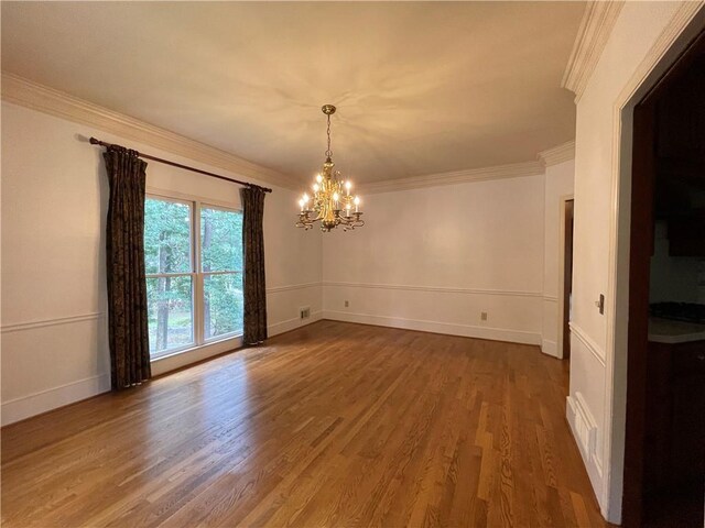 spare room featuring a notable chandelier, hardwood / wood-style floors, and ornamental molding