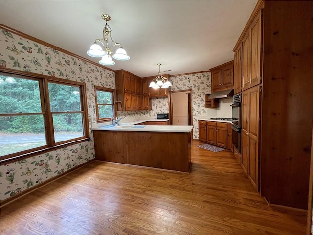 kitchen featuring light wood-type flooring, kitchen peninsula, a chandelier, and decorative light fixtures