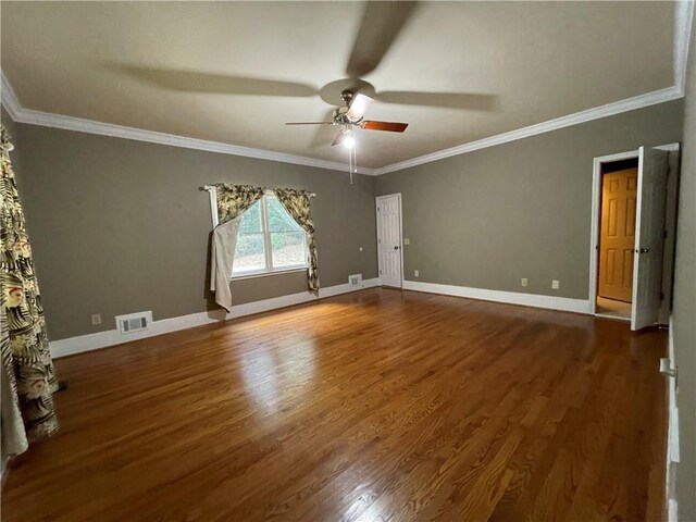 empty room with ornamental molding, dark wood-type flooring, and ceiling fan