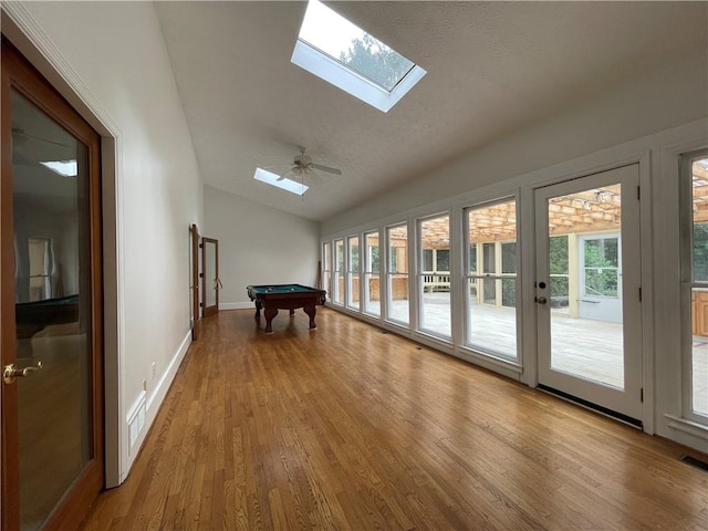 interior space featuring light hardwood / wood-style floors, vaulted ceiling with skylight, ceiling fan, french doors, and pool table