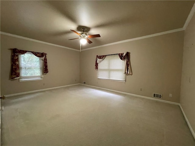 carpeted spare room featuring ornamental molding, ceiling fan, and a healthy amount of sunlight