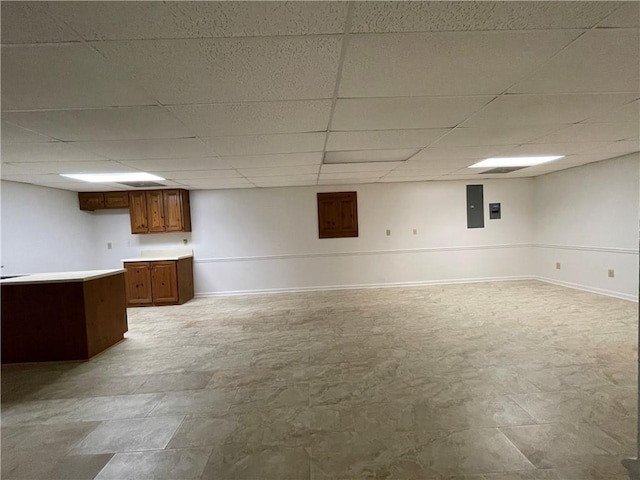 basement with a drop ceiling and electric panel