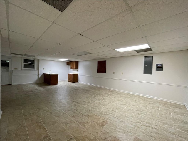 basement with electric panel and a paneled ceiling