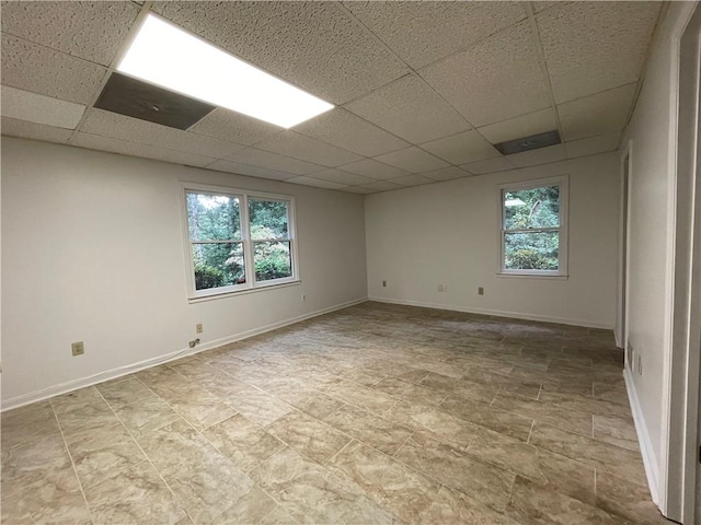 unfurnished room with a paneled ceiling and a wealth of natural light