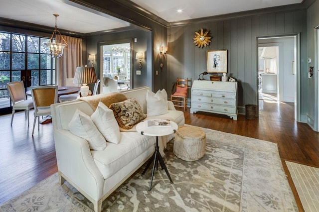 living area with wood finished floors, an inviting chandelier, and ornamental molding