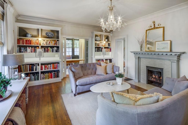 living room featuring ornamental molding, a notable chandelier, wood finished floors, and a fireplace