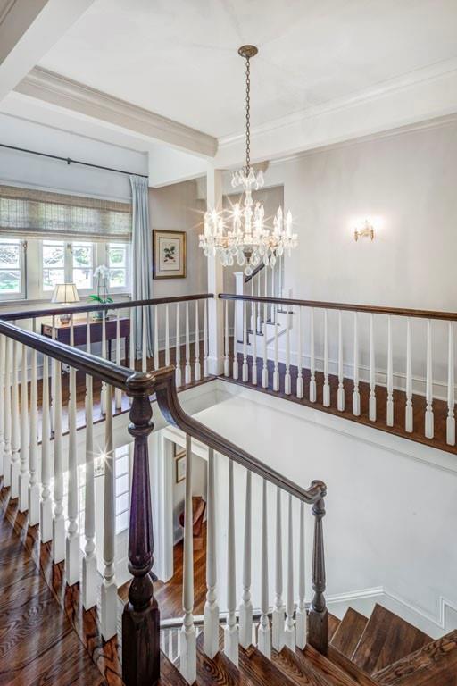 stairs with a chandelier, crown molding, beam ceiling, and wood finished floors