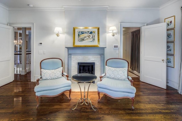 sitting room with a brick fireplace, crown molding, and wood finished floors