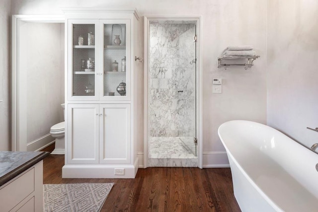 bathroom with a soaking tub, baseboards, a stall shower, and wood finished floors