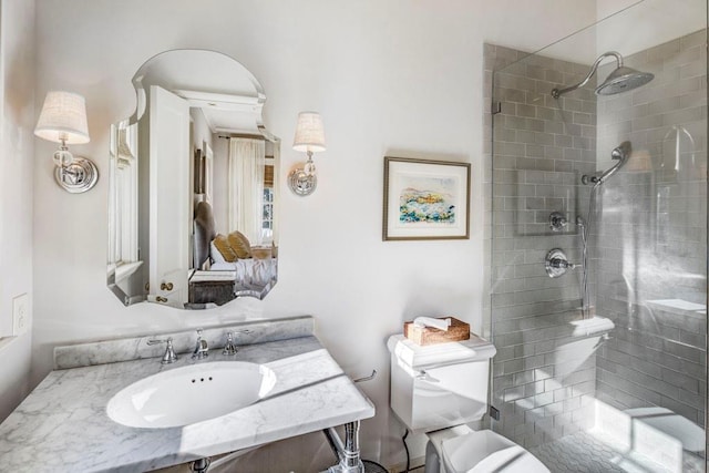 full bathroom with a tile shower, vanity, and toilet