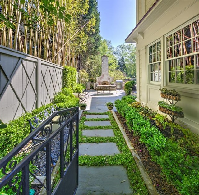 view of yard featuring a patio area, an outdoor stone fireplace, and fence