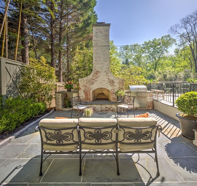 view of patio / terrace with an outdoor living space with a fireplace, fence, and a grill