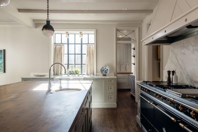 kitchen featuring under cabinet range hood, double oven range, a sink, and beam ceiling