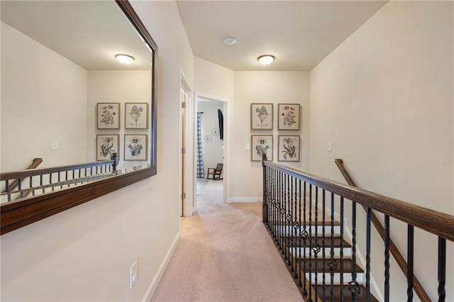 corridor with baseboards, carpet flooring, and an upstairs landing