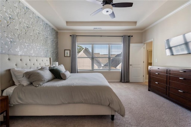 bedroom with ceiling fan, visible vents, crown molding, light colored carpet, and a tray ceiling