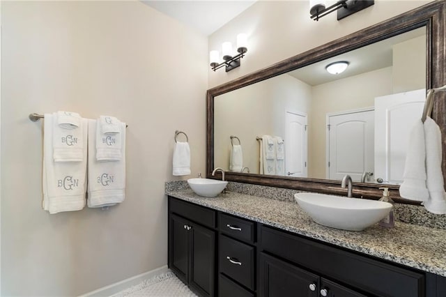 full bathroom featuring double vanity, baseboards, and a sink
