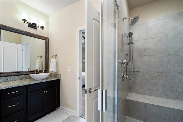 ensuite bathroom with vanity, baseboards, ensuite bath, and tiled shower