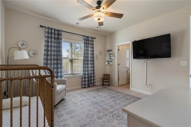 bedroom with a ceiling fan, visible vents, a nursery area, baseboards, and light carpet