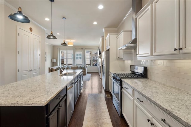 kitchen featuring crown molding, a sink, appliances with stainless steel finishes, and open floor plan