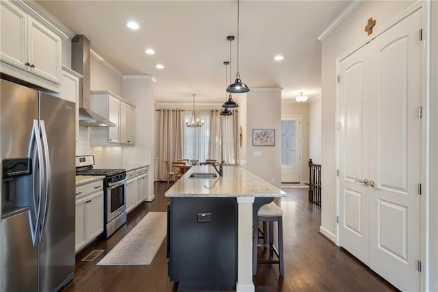 kitchen featuring crown molding, an island with sink, wall chimney exhaust hood, backsplash, and stainless steel appliances