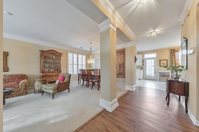 carpeted living room featuring a healthy amount of sunlight, wood finished floors, an inviting chandelier, and ornamental molding