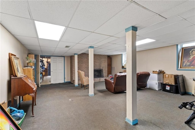 basement featuring carpet floors, a fireplace, and a paneled ceiling