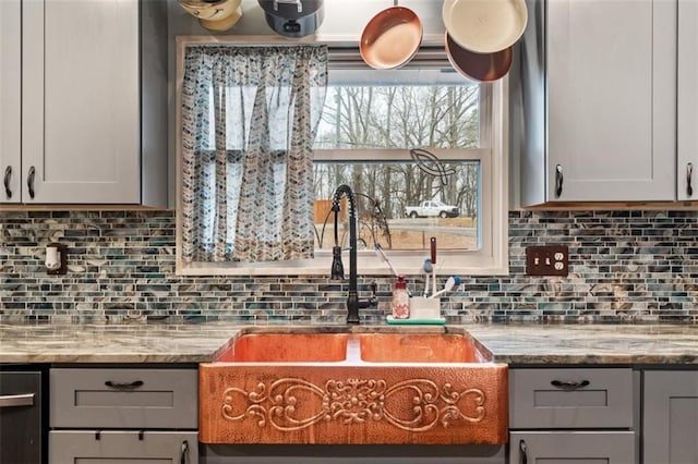 kitchen featuring tasteful backsplash, gray cabinets, sink, and light stone countertops