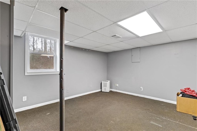 basement featuring dark carpet and a drop ceiling