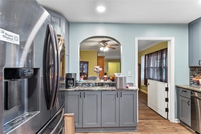 kitchen with ceiling fan, stone counters, gray cabinetry, stainless steel appliances, and light hardwood / wood-style floors