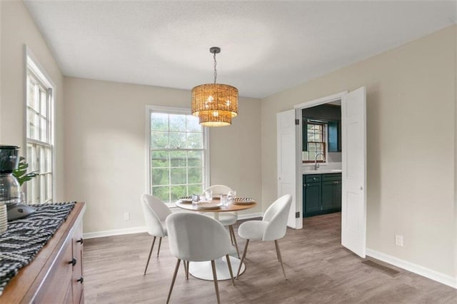 dining room with sink, an inviting chandelier, and hardwood / wood-style flooring