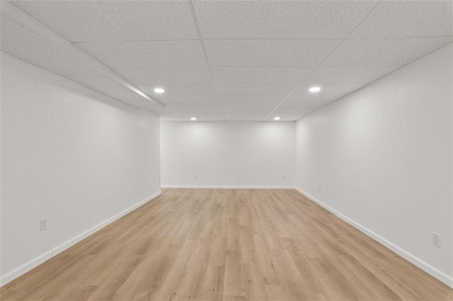 spare room with a paneled ceiling and light wood-type flooring