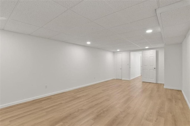 basement with a drop ceiling and light wood-type flooring