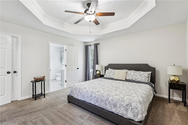 carpeted bedroom with baseboards, ornamental molding, a raised ceiling, and ensuite bathroom