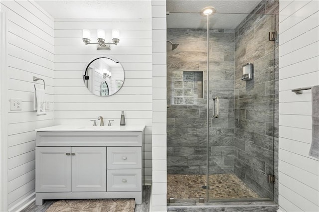 full bathroom featuring a stall shower, a textured ceiling, and vanity