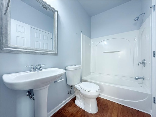 bathroom featuring bathing tub / shower combination, hardwood / wood-style floors, and toilet