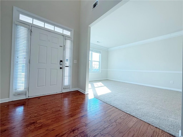 foyer featuring crown molding and carpet