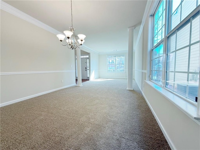 spare room featuring crown molding, a chandelier, decorative columns, and carpet