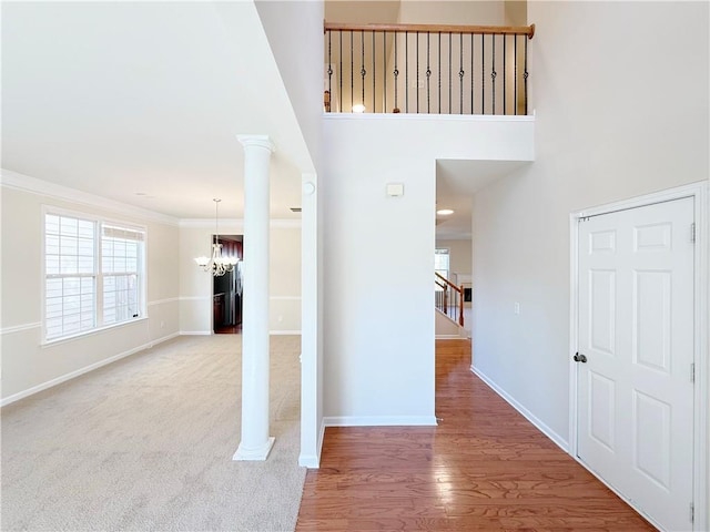 interior space featuring crown molding, a notable chandelier, hardwood / wood-style flooring, and ornate columns