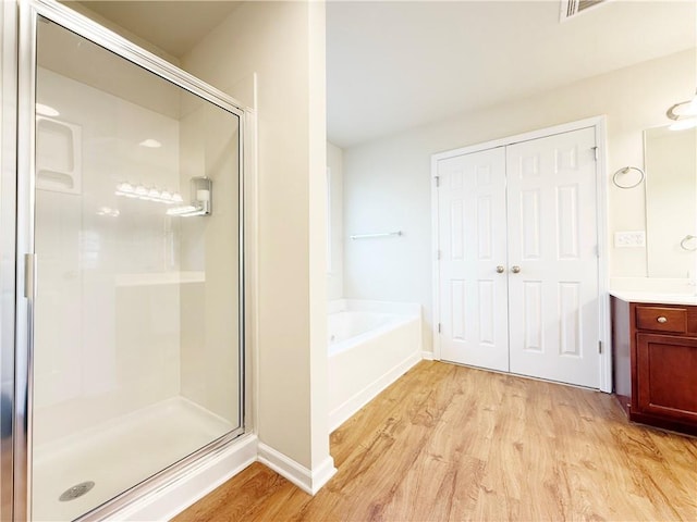 bathroom with hardwood / wood-style flooring, vanity, and shower with separate bathtub