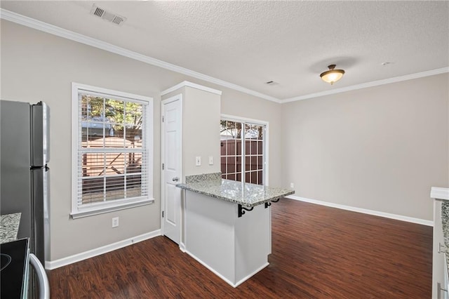 kitchen featuring visible vents, baseboards, dark wood finished floors, a peninsula, and freestanding refrigerator