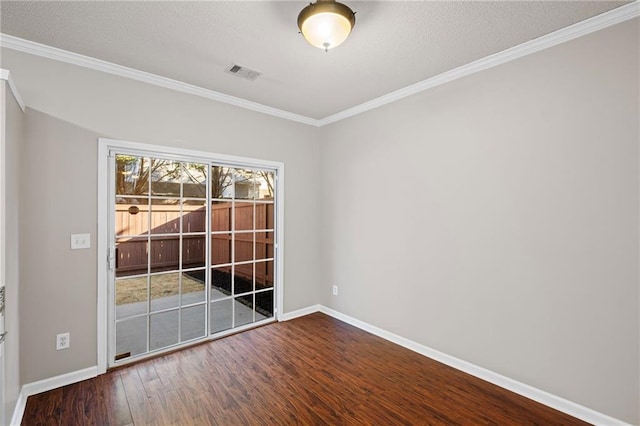 spare room featuring wood finished floors, baseboards, visible vents, and ornamental molding