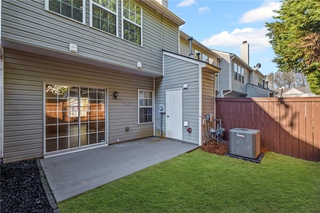 rear view of property featuring a patio, a yard, fence, and central AC